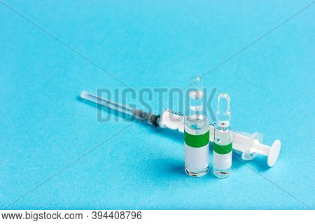 Syringe And Three Ampoules On A Blue Background. Antivenom In Ampoules. Coronavirus Vaccine.