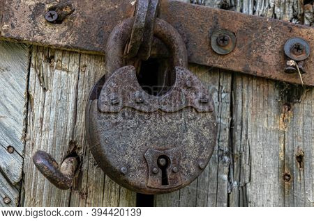 Old rust lock on the door. Metal lock on the gate of an old farmhouse. True village style. Rust steel latch locked with iron lock