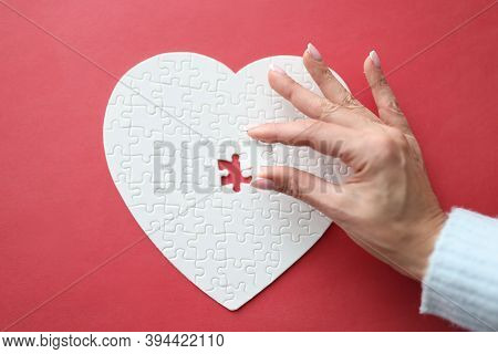 Female Hand Holding White Piece Of Puzzle In Shape Of Heart Close-up. Happy Valentines Day Greetings