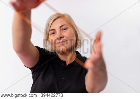 Portrait Of A Woman Stretching A Fitness Elastic Band With Her Hands And Posing. Photo On A White Ba