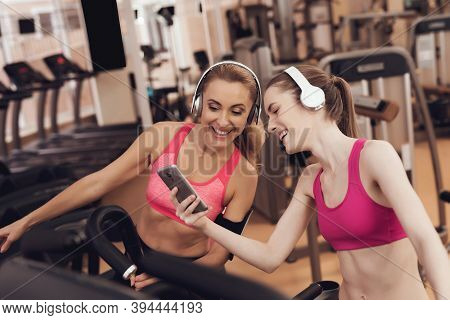 Mother And Daughter Running On Treadmill At The Gym. They Look Happy, Fashionable And Fit.