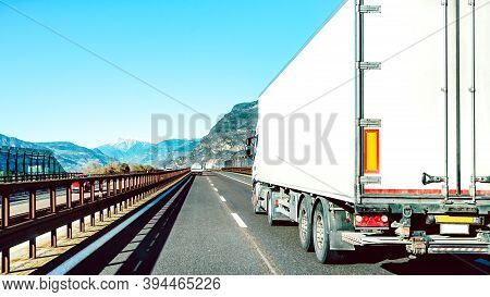 Semi Truck Speeding On Empty Highway Line - Transport Logistic Concept With Semitruck Container Driv