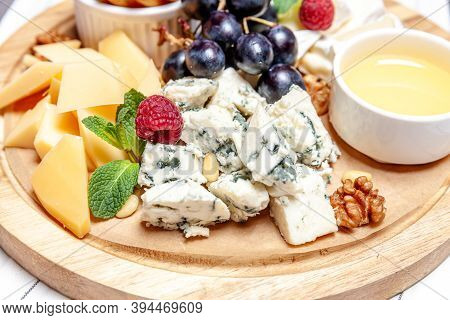 Board With Different Types Of Cheese. Cheeses Mix Set Dor Blu Chedar Parmesan Brie Honey Sauce Finge