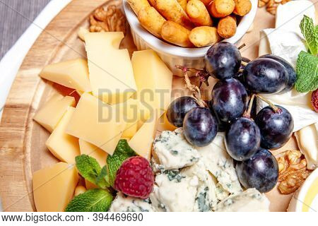 Board With Different Types Of Cheese. Cheeses Mix Set Dor Blu Chedar Parmesan Brie Honey Sauce Finge