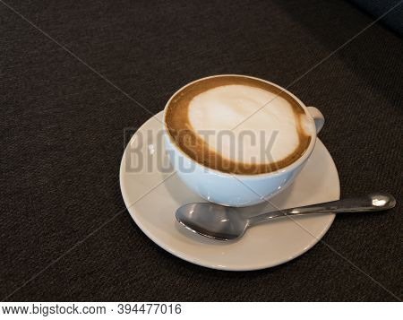 Coffee In White And Stanless Spoon On Black Fabric Background.copy Space.