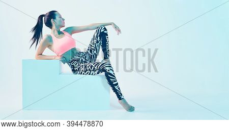 Fitness Girl Posing In Sport Clothes In Neon Light. Fit Young Model With Perfect Body Shapes. Health