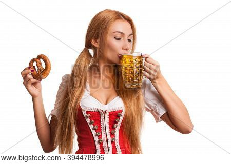 Portrait Of A Gorgeous Sexy Bavarian Girl Sipping Delicious Beer From A Mug, Holding Pretzel, Isolat