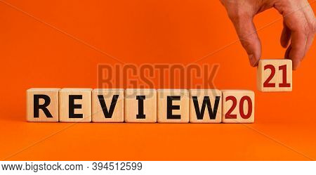 Wooden Cubes With The Inscription 'review 2021'. Male Hand. Beautiful Orange Background, Copy Space.
