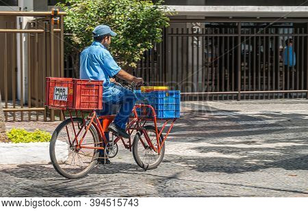 Rio De Janeiro, Brazil - December 23, 2008: Closeup Of Man In Blue Garb On His Red Bicycle Deliverin