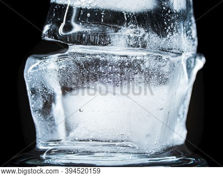 Ice Melts And Rotates On A Black Background. Extreme Close Up. Crystal Ice Cube With Frozen Water Th