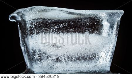 Ice Melts And Rotates On A Black Background. Extreme Close Up. Crystal Ice Cube With Frozen Water Th