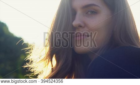 Stunning Girl Face Against Sun With Her Hair Blowing In The Wind. Media. Close Up Of Young Woman Pos