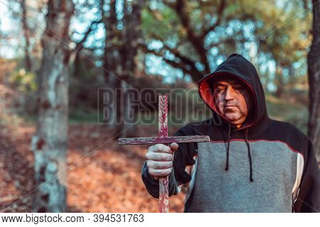 A Man Holds In His Hand A Catholic Cross Casting Out Demons, Exorcism In The Forest