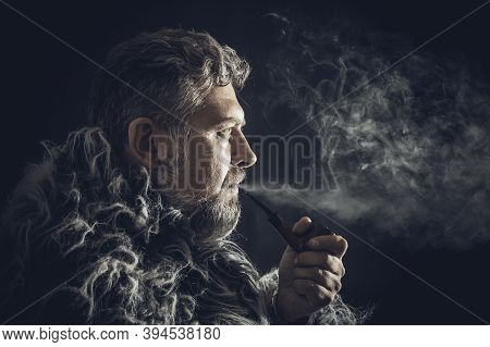Solid Bearded Man In A Fur Mantle Smoking Pipe