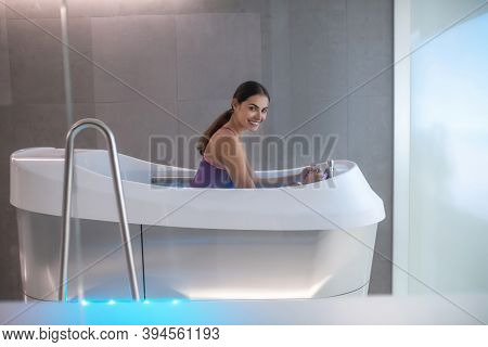 Dark-haired Female Sitting In Hydromassage Bathtub, Enjoying Hydromassage