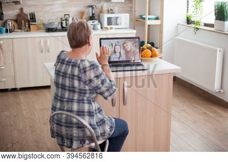 Senior Woman Waving To Her Daughter. Happy Senior Woman During A Video Conference With Family Using 