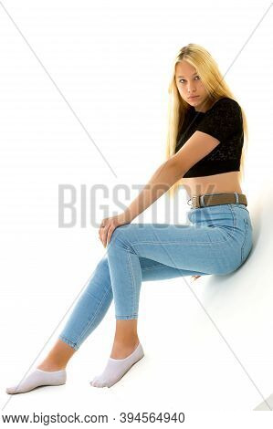 A Cute Little Girl Leaned Against A White Wall. Cyclorama In Studio. Isolated On A White Background.