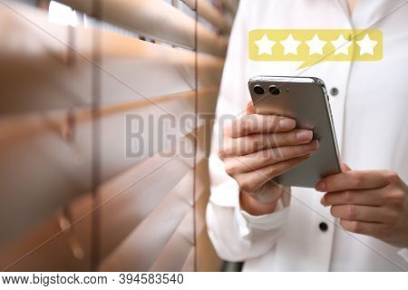 Woman Leaving Review Online Via Smartphone Indoors, Closeup. Five Stars Over Gadget