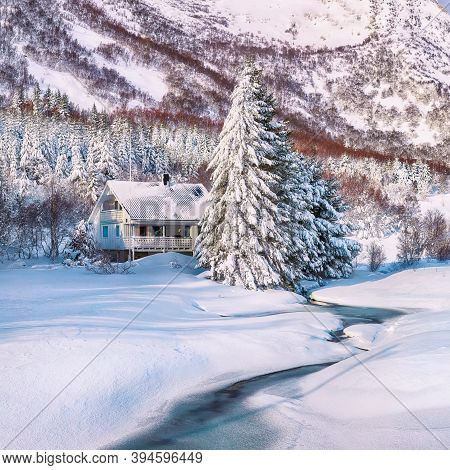 Astonishing Winter Scenery With Frozen River With Wooden Houses And Snow Covered Pine Trees Near Val