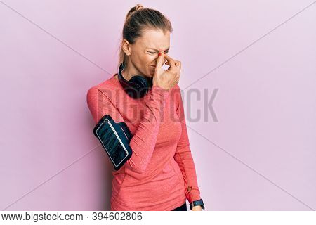 Beautiful caucasian woman wearing sportswear and arm band tired rubbing nose and eyes feeling fatigue and headache. stress and frustration concept. 