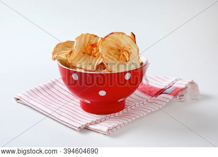 Bowl of dried apple slices - apple chips or rings - on striped tea towel