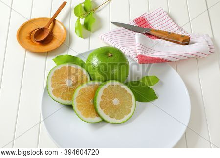 Sweetie fruit (green grapefruit, pomelit) - whole fruit and slices - on white plate