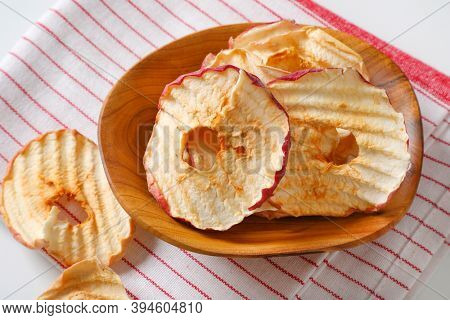 Bowl of dried apple slices - apple chips or rings - on striped tea towel