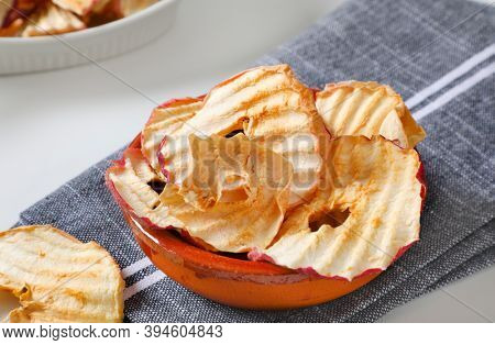 Bowl of dried apple slices - apple chips or rings - on gray napkin