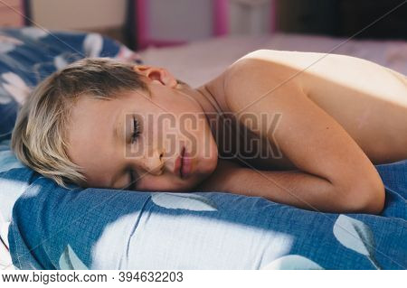 Cute Little Boy Sleep Sweetly On Pillow With Bright Morning Sunbeams From Window, Taking A Nap. Happ