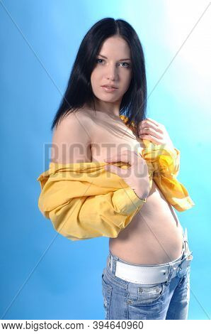 Sexy Beautiful Woman With Blue Eyes Wearing Yellow Shirt And Distressed Jeans In A Blue Background