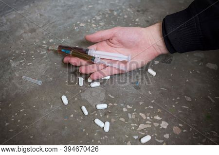 Addict Hand With Syringe And Pills On The Floor. International Drug Abuse Day. Addiction Concept
