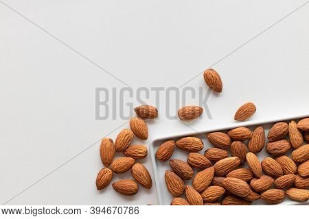 Fresh Almonds Nuts In A Flat White Plate And Scattered On The Table