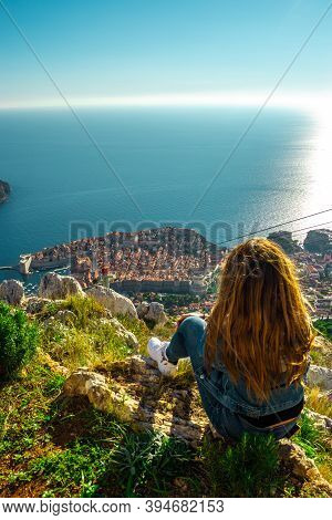 Vertical Shot Of A Brunette Girl Sitting On Top Of The Srd Mountain Looking Down At The Ancient Croa
