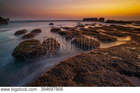 Amazing Seascape For Background. Beach With Rocks And Stones. Low Tide. Motion Water. Clear Sky. Sun