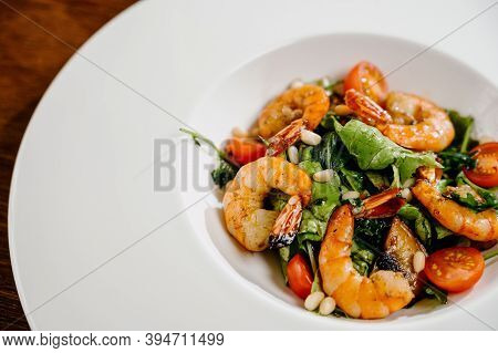 Fresh Salad Plate With Shrimp, Tomato And Mixed Greens On Wooden Background Close Up. Healthy Food.