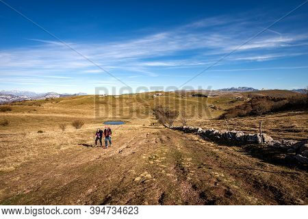 Altopiano Della Lessinia, Italy - Nov 8, 2020: Two Senior Adults Hiking On The Lessinia Plateau Towa