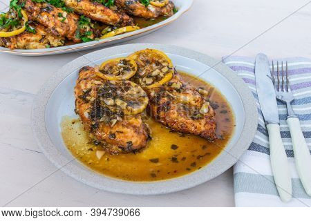 Chicken Francese - Fried Chicken Breast With Lemon Slices And Delicious Sauce On A White Plate On Th