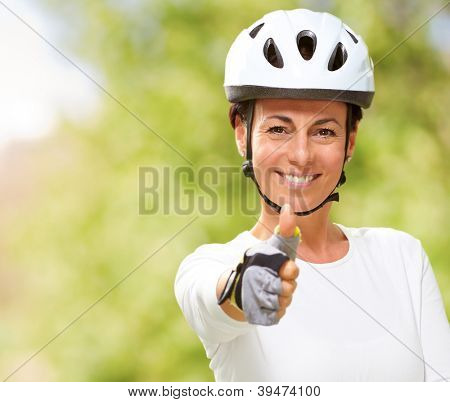Femme portant casque montrant le pouce vers le haut, en plein air