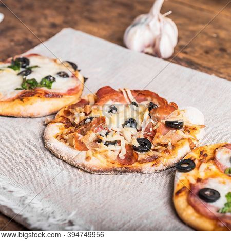 Several Ready-made Mini Pizza, Pizzetta On A Linen Napkin On A Wooden Table