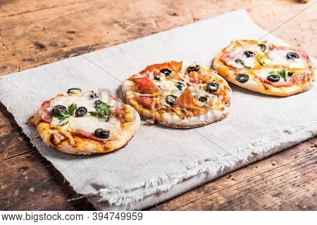 Several Ready-made Mini Pizza, Pizzetta On A Linen Napkin On A Wooden Table