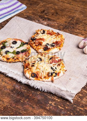 Several Ready-made Mini Pizza, Pizzetta On A Linen Napkin On A Wooden Table