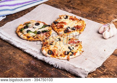 Several Ready-made Mini Pizza, Pizzetta On A Linen Napkin On A Wooden Table