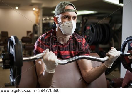 Young Caucasian Man Working Out In An Indoor Gym, Barbell Bicep Curl Exercise, Wearing Protective Fa