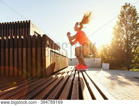 Side View Full Body Of Determined Young Fit Female In Sportswear And Headphones Jumping Over Stairs 
