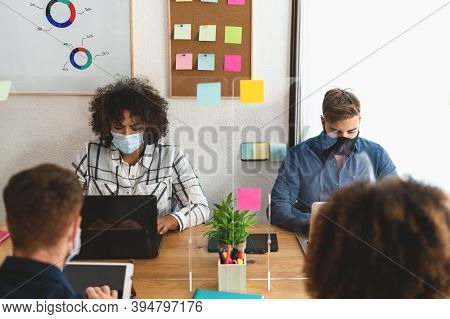 Young People In Co-working Creative Space Wearing Surgical Mask And Keeping Social Distance To Avoid