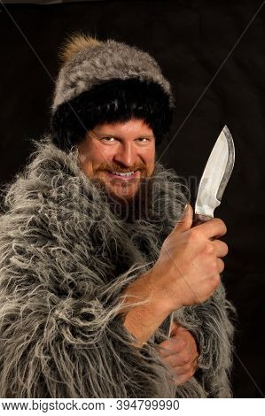 Bearded Hunter Dressed In A Fur Mantle And Fur Hat With Knife