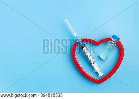 Heart Injection And Vaccine Vial. Covid 19 Cure. Medical Ampoule Dose And Needle On Blue Background,