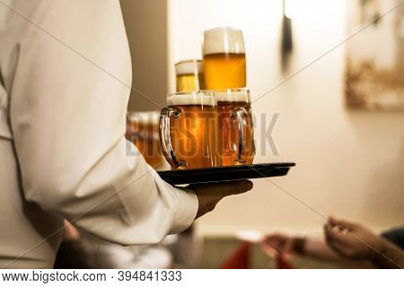Different Beer Drinks On A Plate Served By Waiter In A German Biergarten Beergarden