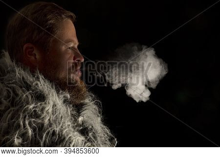 Solid Bearded Man Dressed In A Fur Mantle Exhaling Vapour