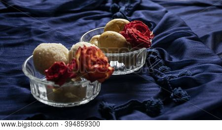 Picture Of Delicious Besan Laddu Decorated In Bowl With Fresh Red Roses In A Blue Background. Besan 